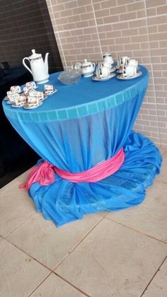 a table covered in blue tarp with tea cups on it