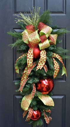 a christmas wreath with red and green ornaments hanging on the front door's black door