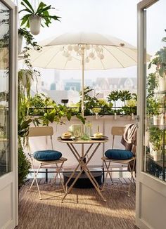 there are plants and chairs on the balcony with an open umbrella over them, hanging planters