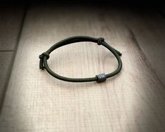 a green leather bracelet sitting on top of a wooden floor