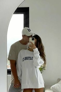 a man and woman taking a selfie in front of a mirror while wearing matching clothes