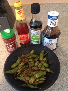 green beans in a black bowl next to condiments and seasonings on a counter