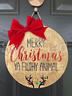 a merry christmas ya filthy animal sign hanging on a door with a red bow around it