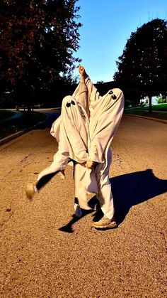 a person in a white outfit is doing a trick on the street with his hands