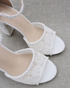 a pair of white wedding shoes with pearls on the heel and lace trimmings