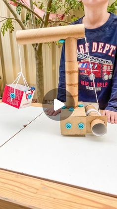 a young boy standing next to a table with a wooden toy on top of it