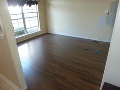 an empty room with hard wood flooring in the foreground and a window on the far wall