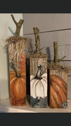 three painted pumpkins sitting on top of a shelf