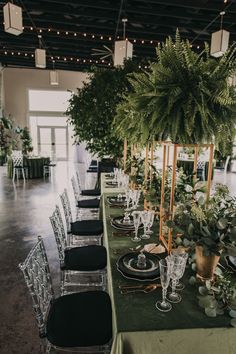 a long table is set up with place settings and greenery