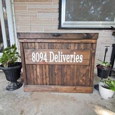 a wooden box with the words 994 deliveries written on it and two potted plants next to it