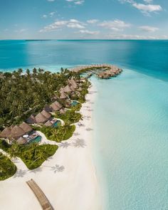 an aerial view of the beach and resort in the middle of the ocean, surrounded by palm trees