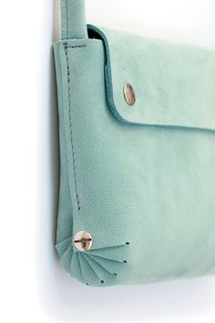 a green purse hanging on the wall with a button in it's center and an eye hole at the bottom