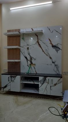 a large white marbled entertainment center in a room with no one around it and wires hanging from the ceiling