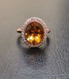 an oval shaped yellow sapphire and diamond ring on top of a black surface with white diamonds around it