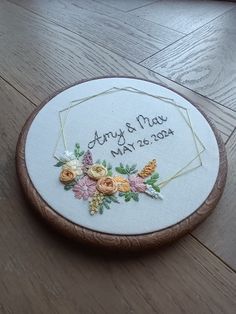 a wooden box with embroidered flowers on the inside and wedding date written in white ink