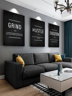 a living room with grey couches and yellow pillows on the coffee table in front of two black framed posters