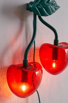 two red lights are attached to a wall with green leaves on the top and bottom