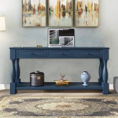 a blue console table with two pictures on the wall above it and a rug underneath