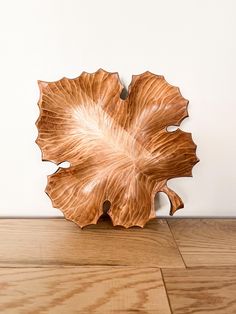 a large leaf shaped bowl sitting on top of a wooden floor