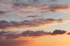 a plane flying in the sky at sunset with clouds and sun going down behind it