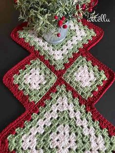 a potted plant sitting on top of a table next to two crocheted squares