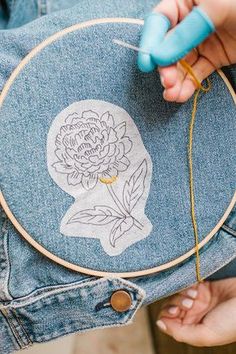 someone is stitching a flower on the back of a pair of denim jeans with a needle