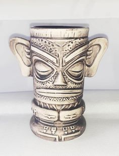 a ceramic cup with an intricate design on the front and sides, sitting on a white surface