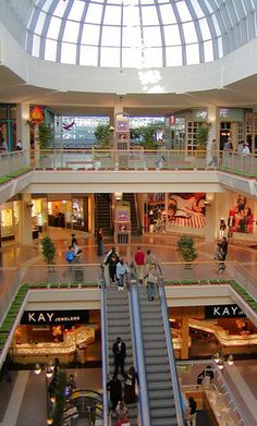 the inside of a shopping mall with escalators and people walking down one floor