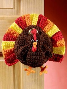 a crocheted turkey hat hanging on a doorknob with a red, yellow and orange stripe