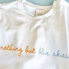 White T-shirt with embroidered 'Nothing but blue skies' on the front in orange & blue embroidery 100% soft organic cotton in a relaxed fit. *Eco-Friendly tee from a sustainable and ethical wholesaler* Sizes: Small (6/8) to fit chest 30/32 Medium (10/12) to fit chest 32/34 Large (14/16) to fit chest 34/36 XLarge ( 18/20) to fit chest 36/38 XXLarge (22/24) to fit chest 28/40 I am a size 12/14 and like to wear a large which is an oversize fit on me. Each item is made to order especially for you, so if you need extra measurements please let me know before you place your order :-) Casual Blue T-shirt With Letter Embroidery, Blue T-shirt With Embroidered Text For Spring, Blue Tops With Embroidered Text And Relaxed Fit, Blue Relaxed Fit Top With Embroidered Text, Blue Embroidered Relaxed Fit T-shirt, Blue Graphic Tee With Embroidered Text, Blue Relaxed Fit T-shirt With Embroidered Text, Summer Everyday T-shirt With Embroidered Text, Blue Embroidered T-shirt For Summer