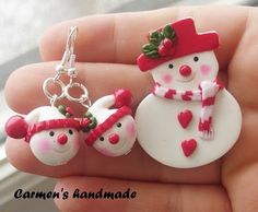 two snowmen wearing red hats and scarfs on their heads are hanging from a pair of earrings