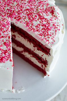 a red velvet cake with white frosting and sprinkles on a plate