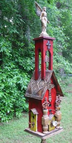 a red bird house with a statue on top