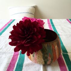 a large red flower sitting in a vase on top of a bed