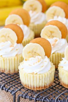 cupcakes with banana slices and whipped cream frosting sitting on a cooling rack