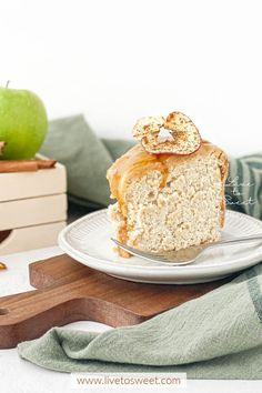 a piece of cake sitting on top of a white plate next to an apple and wooden cutting board