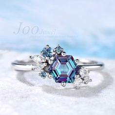 an engagement ring with blue and white diamonds on it, sitting in the middle of snow