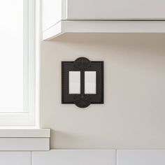 two light switch plates mounted to the side of a white kitchen counter top next to a window