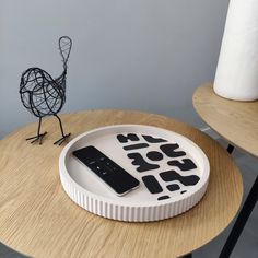 a cell phone sitting on top of a white plate next to a black bird statue