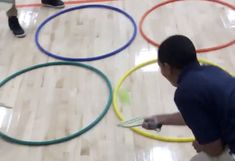 a man standing in front of a bunch of colorful hula hoops on top of a wooden floor