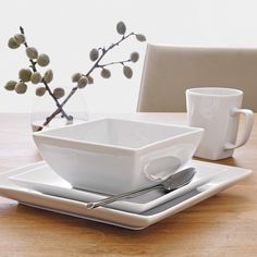 a white square bowl on a plate with silverware