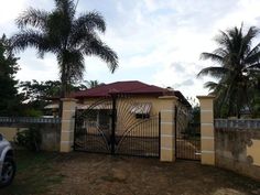 a car is parked in front of a gated house with palm trees behind it