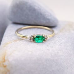 Introducing our Dainty Emerald Ring, a lovely choice for May birthdays or special moments. This minimalist gold ring features a lab-created emerald gemstone in an elegant oval cut. It's a delicate and charming option for an engagement or as a birthstone ring. The small emerald stone is accented with diamonds, adding a touch of sparkle. Celebrate love and life with this exquisite, understated gem. Key Features: * Gemstone: Chatam Lab Created Emerald Stone * Gemstone: Measurements: 1 Piece | Oval Cut 0.30ct * Side Gemstones: 100% Natural Diamonds * Side Gemstones Measurements: 6 Pieces | Round Cut 0.03ct * Material: High-Quality Solid Gold 14k ------CUSTOMIZATION------ ♥ Feel free to contact me for any other customization to your preferences. How to order: * Ordering is easy! Just use the Me Minimalist Oval May Birthstone Rings, Dainty Oval Emerald Ring With Prong Setting, Oval Diamond Birthstone Ring Minimalist, Dainty Oval Emerald Ring For Anniversary, Elegant Oval Cluster Ring With Birthstone, Minimalist Oval Diamond Birthstone Ring, Green Oval Dainty Rings, Oval Stackable Rings For Anniversary, Oval Stackable Promise Rings With Accent Stones