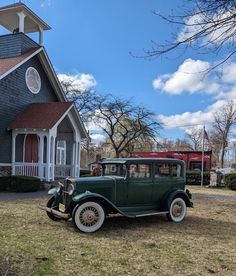 an old green car parked in front of a church