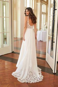 a woman in a white wedding dress standing on a wooden floor looking at the mirror