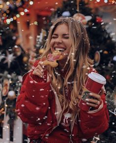 a woman eating a donut and drinking coffee in front of a christmas tree