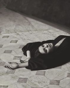 a black and white photo of a woman laying on the floor