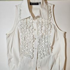 Nwot Inc International Concepts White Sleeveless Ruffle Front Blouse - Size 4. Button Down Front. Plain Back. 60% Cotton/35% Polyester/5% Spandex. 5 Columns Of Ruffles On Each Side Of The Buttons. Great Condition. Approximate Pit-2-Pit Measure = 16.5" 10" Top Of Shoulder To Top Of Shoulder Elegant Summer Tank Top With Buttons, Formal Sleeveless Tops With Buttons, Elegant Spring Tank Top With Buttons, Formal Summer Vest Top, Elegant Sleeveless Blouse With Buttons, Elegant Sleeveless Button Blouse, Elegant Spring Vest With Ruffles, White Formal Sleeveless Top, Elegant White Tank Top With Buttons