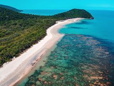 an aerial view of the beach and ocean near some forested hills with trees on each side