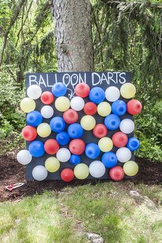 balloon darts are displayed in front of a tree